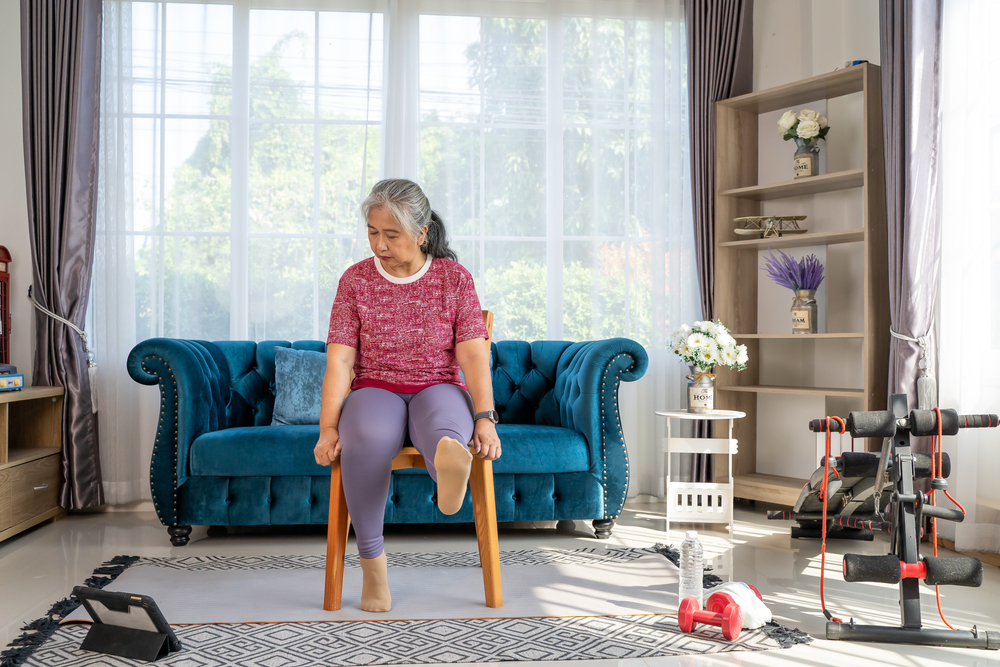 Older woman with arthritis performing knee raises for exercise.